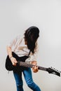 Young long haired guitarist excited playing his black electric guitar, isolated on white background