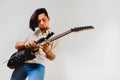 Young long haired guitarist excited playing his black electric guitar, isolated on white background Royalty Free Stock Photo