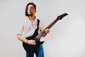 Young long haired guitarist excited playing his black electric guitar,  on white background Royalty Free Stock Photo