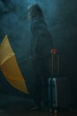 Young long haired man holding yellow umbrella and suitcase Royalty Free Stock Photo