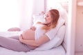 Young long-haired pregnant woman in a white t-shirt touching her belly Royalty Free Stock Photo