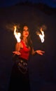 Young long-haired woman in a bright red top and ethnic jewelery holds on handbreadth two small burning torch