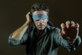 Young lost and confused man blindfolded with necktie playing internet trend dangerous viral challenge with eyes blind on