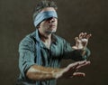 Young lost and confused man blindfolded with necktie playing internet trend dangerous viral challenge with eyes blind on