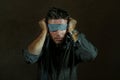 Young lost and confused man blindfolded with necktie playing internet trend dangerous viral challenge with eyes blind on