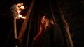 Young lost woman with long hair standing in forest at night with a handmade torch