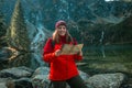 Young lost woman traveler with map and backpack relaxing outdoor with rocky on Morskie Oko lake. Woman traveler explorer Royalty Free Stock Photo