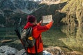 Young lost woman traveler with map and backpack relaxing outdoor with rocky on Morskie Oko lake. Woman traveler explorer Royalty Free Stock Photo