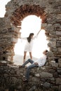 Young in love couple sitting inside brick archway of old building