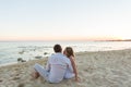 Young love couple sitting together on beach, rear view Royalty Free Stock Photo