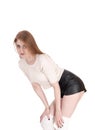 Woman standing in leather shorts bending forwards