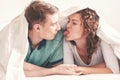 Young lovely couple in bed having fun covered with soft warm white blanket, Happy playful caucasian lovers relaxing in comfortable Royalty Free Stock Photo