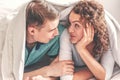 Young lovely couple in bed having fun covered with soft warm white blanket, Happy playful caucasian lovers relaxing in comfortable Royalty Free Stock Photo