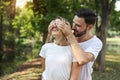 Young lovely couple caucasian in white dress playing blindfolded with happy face and laughing in park outdoor during summer Royalty Free Stock Photo