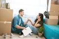 Young lovely couple man and woman looking satisfied sitting on the floor drinking champagne during moving to new apartment Royalty Free Stock Photo