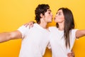 Young lovely couple posing together making selfie and kissing over yellow background Royalty Free Stock Photo