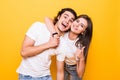 Young couple posing together while making selfie and woman showing thumb up, over yellow background