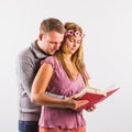 Young couple reading book together or looking at notes or drawings. Studio shot on white background Royalty Free Stock Photo