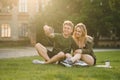 Young lovely couple of students sitting in the college park and taking selfie on the smartphone. Smiling cheerful students couple Royalty Free Stock Photo