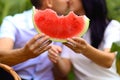 Young, lover`s couple holding a watermelon and kissing, a picnic on the sunflower field Royalty Free Stock Photo