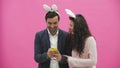 Young lovers couple on pink background. With ravenous ears on the head. During this Easter photo, sephi do on the phone