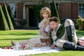 Young lovers dressed in vintage clothing sitting on picnic blanket. Gentleman reading to his lover from a book of poems Royalty Free Stock Photo