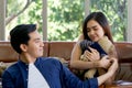 Young lovers spend time together on holidays in the living room. The young man wears comfortable clothes, hand a teddy bear to