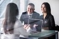 Buying something special. Young loving couple bonding to each other and looking at woman sitting in front of them at the desk Royalty Free Stock Photo