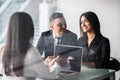 Buying something special. Young loving couple bonding to each other and looking at woman sitting in front of them at the desk thro Royalty Free Stock Photo