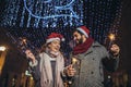 Loving couple burning sparklers by holiday illumination on new years eve