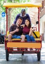 Young loving couple enjoying tour of city on trishaw with affable African American driver