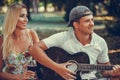 Young loving couple having fun with guitar during picnic in the park Royalty Free Stock Photo