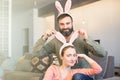 Young loving couple having fun with pink rabbit ears on head. Happy family preparing for Easter.