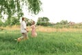 Young loving couple having fun and running on the green grass on the lawn with their beloved domestic dog breed Beagle and a Royalty Free Stock Photo