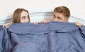 Young loving couple hiding faces under blanket in bed and looking into eyes Royalty Free Stock Photo