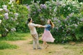 Young loving couple holding hands and spinning in the lilac garden