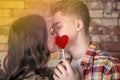Young, loving couple, kiss each other, cover their lips with a candy in the form of a heart, Teenagers, gentle kiss