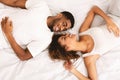 Young loving couple lying in bed together and looking at camera Royalty Free Stock Photo