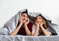Young loving couple lying in bed under blanket Royalty Free Stock Photo