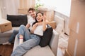 Young loving couple moving to a new house. Home and family concept. They are sitting on the sofa and looking at their Royalty Free Stock Photo