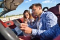 Young loving couple planning their romantic adventure. Joyful young couple smiling while riding in their convertible Royalty Free Stock Photo