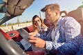 Young loving couple planning their romantic adventure. Joyful young couple smiling while riding in their convertible