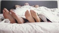 Young loving couple shows feet under blanket while wake up in bed in the morning Royalty Free Stock Photo