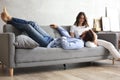 Young loving couple relaxing on sofa together, husband lying on wife legs resting on couch