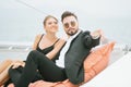 Young loving couple sitting on deck of sailboat during sea trip, looking far away and pointing to horizon. Young couple enjoying Royalty Free Stock Photo