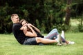 Young loving couple is sitting on grass in the park, hugging, fooling around and enjoying nature Royalty Free Stock Photo