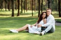 young loving couple is sitting on grass in the park, hugging, fooling around and enjoying nature Royalty Free Stock Photo