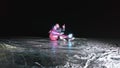 Young loving couple skating at ice rink at night. Man and woman kiss hug have fun learn to skate. Making love on ice