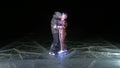 Young loving couple skating at ice rink at night. Man and woman kiss hug have fun learn to skate. Making love on ice