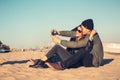 A young loving couple spends fun time by the sea and makes selfies. Man and woman have spring clothes